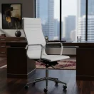 Silla de oficina ergonómica blanca frente a escritorio de madera oscura en oficina gerencial con ventanal de fondo.