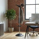 Perchero de pie Elix para oficina en ambiente moderno, estructura metálica con base circular y ganchos para chaquetas y sombreros.