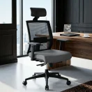 Silla ergonómica negra con asiento de tela gris y respaldo de malla en oficina gerencial.