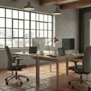 Estación grupal de oficina con cubierta color madera y base metálica gris, ideal para puestos de trabajo modernos.