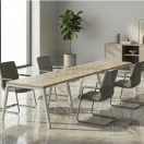 Mesa de reunión Enio en madera con base blanca ambientada en sala de juntas moderna