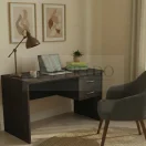 Escritorio de madera oscura con cajonera lateral y silla de oficina gris en habitación.
