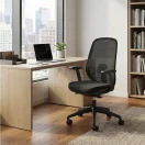 Silla de escritorio Slim en ambiente de oficina moderna junto a escritorio de madera, respaldo en malla color negro.
