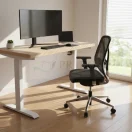 Escritorio de oficina ajustable en altura con cubierta de madera clara y monitor ultra ancho en ambiente home office.