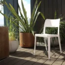 Silla Minimal blanca sin apoyabrazos en una terraza exterior con plantas