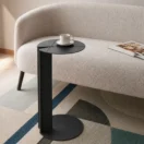 Mesa lateral Aqua negra junto a un sofá bouclé en un living con alfombra geométrica