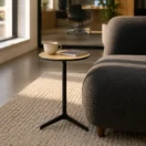Mesa lateral Vector de base tripode junto a un sofa boucle gris en un area lounge con luz natural